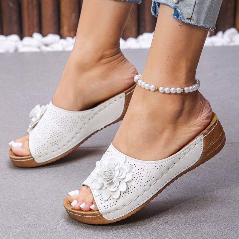 White - Women's slip-on wedge sandals featuring a perforated upper with a 3D floral applique and contrast stitching.