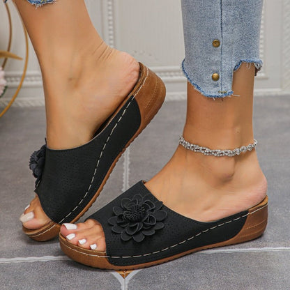 Black - Women's slip-on wedge sandals featuring a perforated upper with a 3D floral applique and contrast stitching.