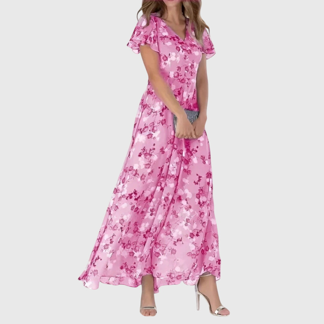 Light Pink - Woman wearing a peach watercolor floral chiffon maxi dress with flutter sleeves and a V-neckline, styled with metallic heels.
