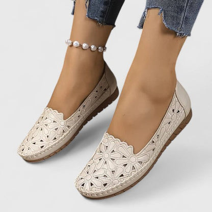 Beige - Women's slip-on loafers featuring a faux-leather upper with detailed floral cutouts, scalloped edges, and a textured flat sole.