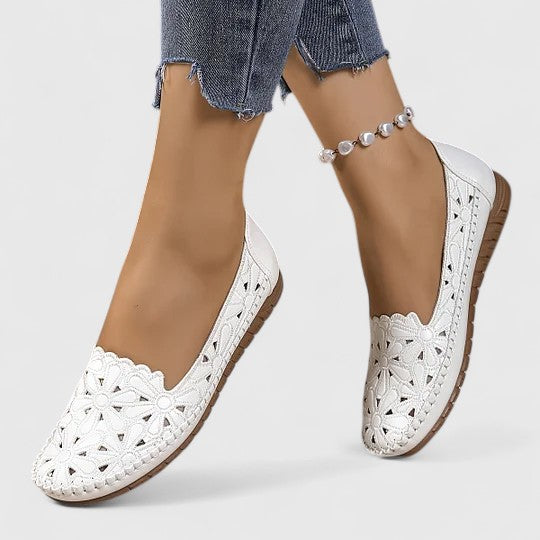 White - Women's slip-on loafers featuring a faux-leather upper with detailed floral cutouts, scalloped edges, and a textured flat sole.