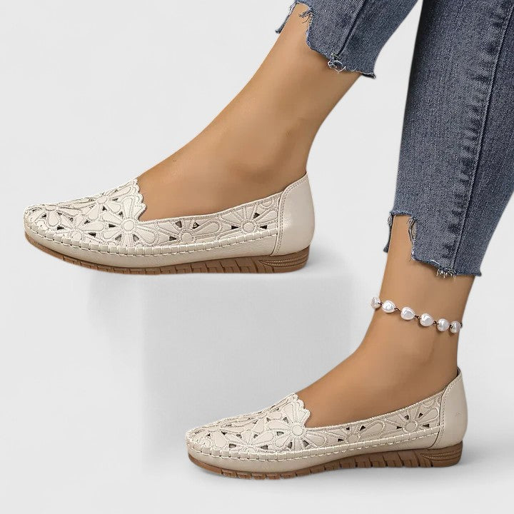 White - Women's slip-on loafers featuring a faux-leather upper with detailed floral cutouts, scalloped edges, and a textured flat sole.