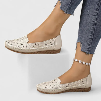 White - Women's slip-on loafers featuring a faux-leather upper with detailed floral cutouts, scalloped edges, and a textured flat sole.