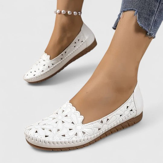 White - Women's slip-on loafers featuring a faux-leather upper with detailed floral cutouts, scalloped edges, and a textured flat sole.
