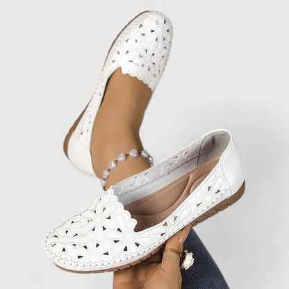 White - Women's slip-on loafers featuring a faux-leather upper with detailed floral cutouts, scalloped edges, and a textured flat sole.