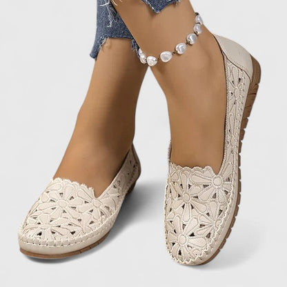 White - Women's slip-on loafers featuring a faux-leather upper with detailed floral cutouts, scalloped edges, and a textured flat sole.
