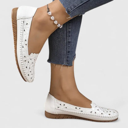 White - Women's slip-on loafers featuring a faux-leather upper with detailed floral cutouts, scalloped edges, and a textured flat sole.