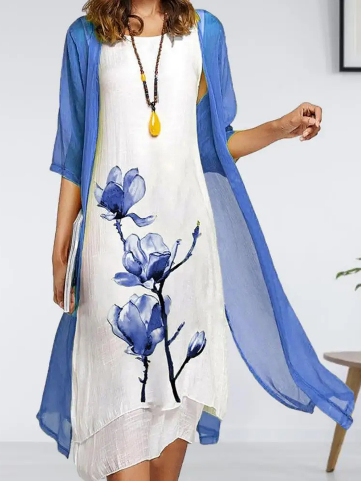 Blue - Woman wearing a sleeveless midi dress with a large floral print and a matching sheer, open-front long cardigan.