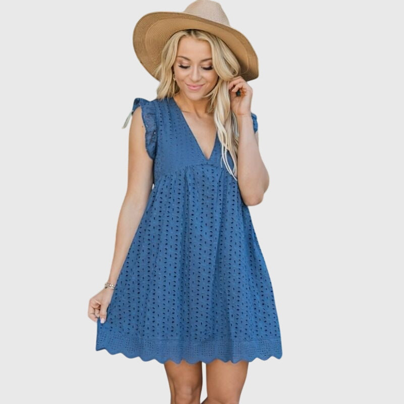 Dark Blue - A woman wearing a black V-neck cotton eyelet mini sundress with flutter sleeves and a scalloped hem, holding a straw clutch.