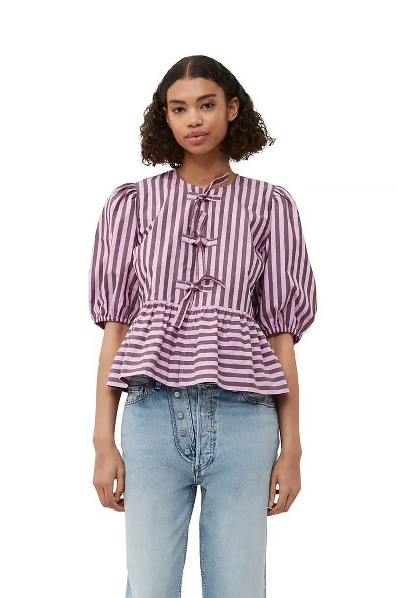 Woman in pink and brown striped blouse and khaki shorts holding sunglasses