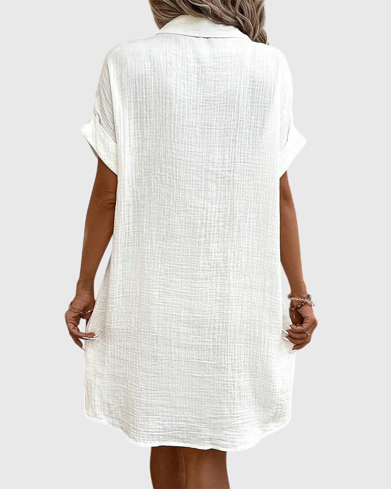 Olive Green - A woman wearing a white, short-sleeved cotton gauze button-down shirt dress with front patch pockets and a pointed collar.
