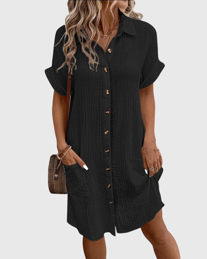Black - A woman wearing a white, short-sleeved cotton gauze button-down shirt dress with front patch pockets and a pointed collar.