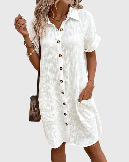 Olive Green - A woman wearing a white, short-sleeved cotton gauze button-down shirt dress with front patch pockets and a pointed collar.