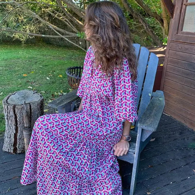 Purple - Woman wearing a long sleeve geometric print tiered maxi dress with puff sleeves walking on a sidewalk