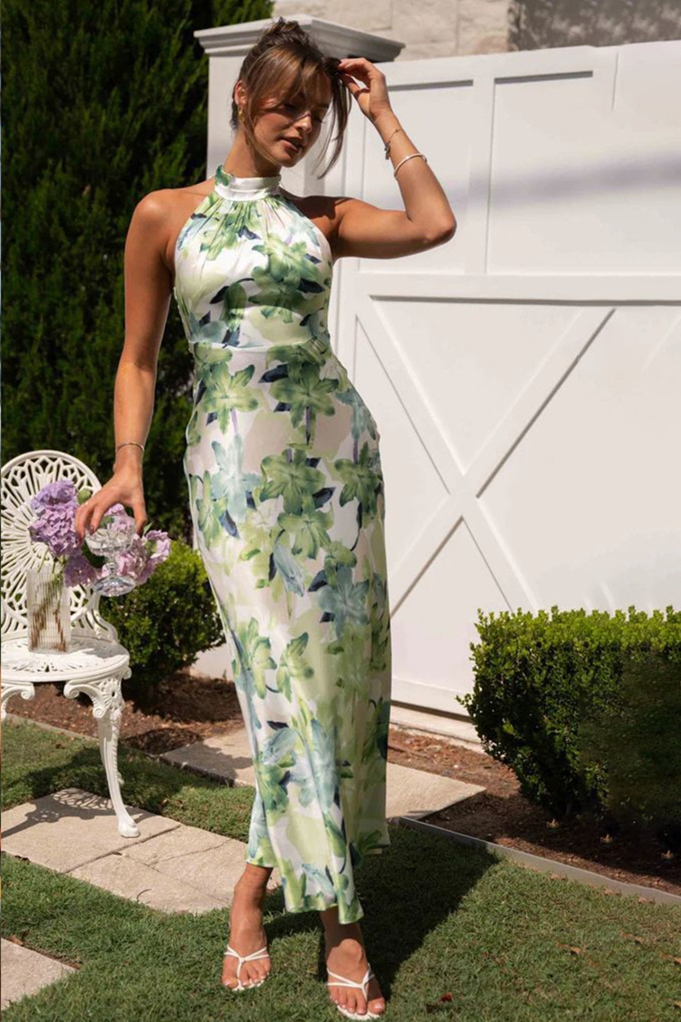 Woman in green floral satin halter maxi dress