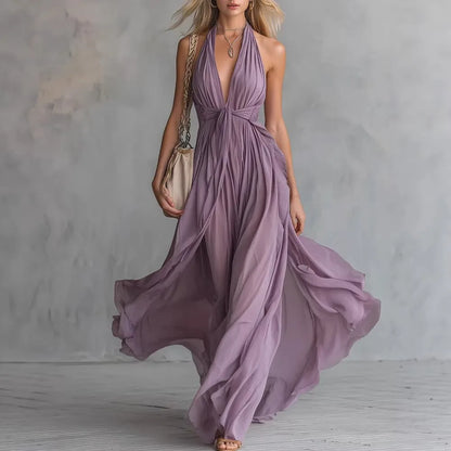 Purple - A woman wearing a dusty lavender chiffon halter maxi dress with a plunging V-neckline, pleated bodice, and a flowing floor-length skirt.