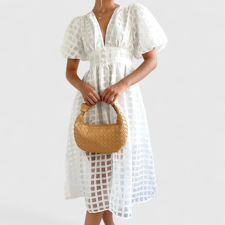White - A woman wearing a black grid organza midi dress with puff sleeves, a deep V-neck, and a button-front bodice, holding a woven beige handbag.