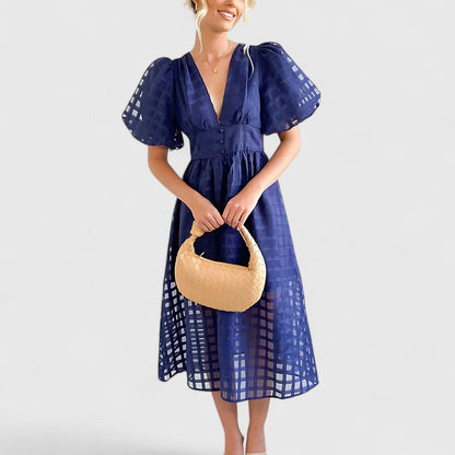 Navy blue - A woman wearing a black grid organza midi dress with puff sleeves, a deep V-neck, and a button-front bodice, holding a woven beige handbag.