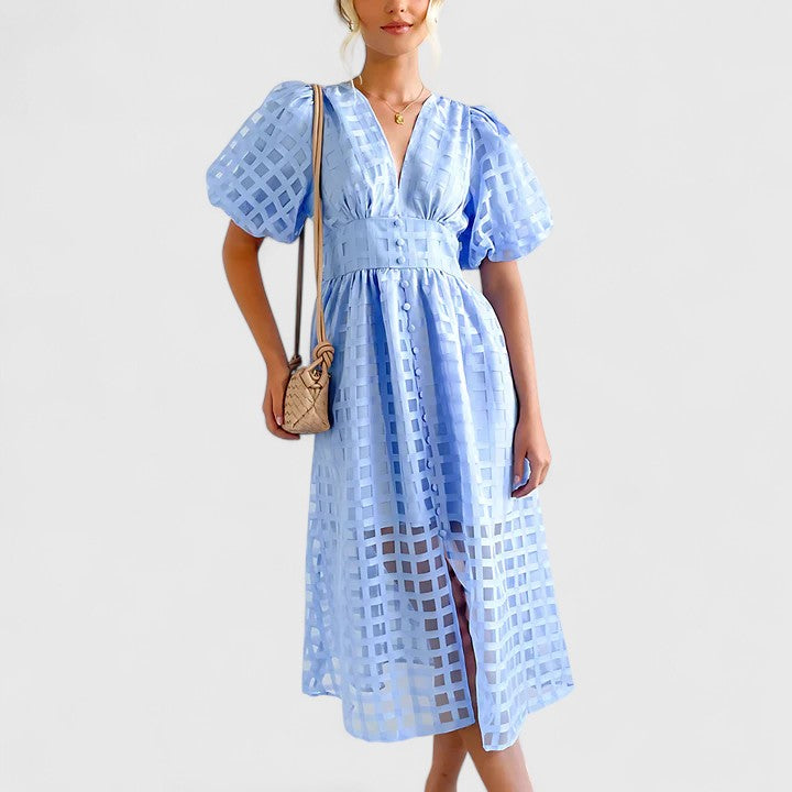 Light blue - A woman wearing a black grid organza midi dress with puff sleeves, a deep V-neck, and a button-front bodice, holding a woven beige handbag.