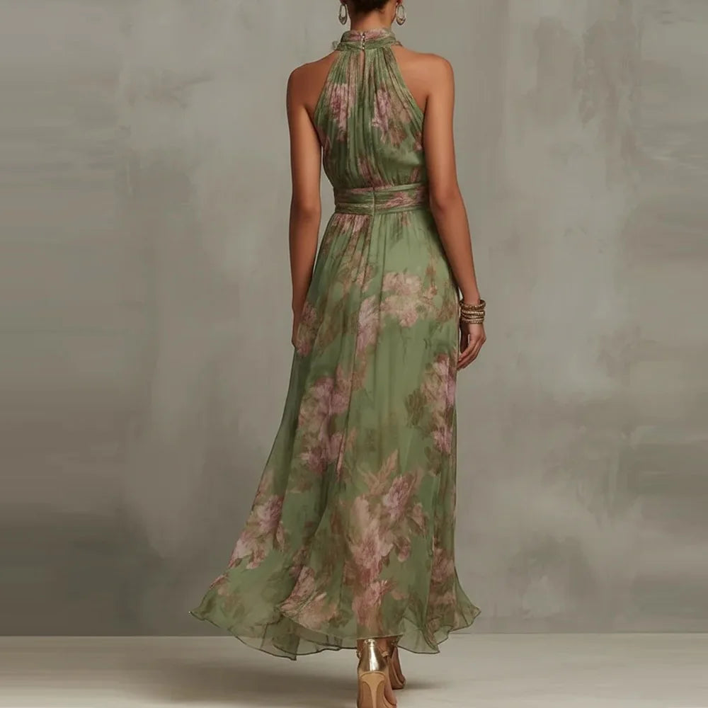 Green - A woman wearing a sage green and dusty pink watercolor floral print chiffon maxi dress with a high halter neck, ruched waist, and flowy floor-length skirt.