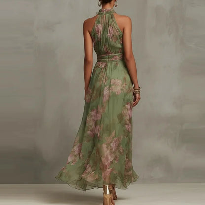Green - A woman wearing a sage green and dusty pink watercolor floral print chiffon maxi dress with a high halter neck, ruched waist, and flowy floor-length skirt.