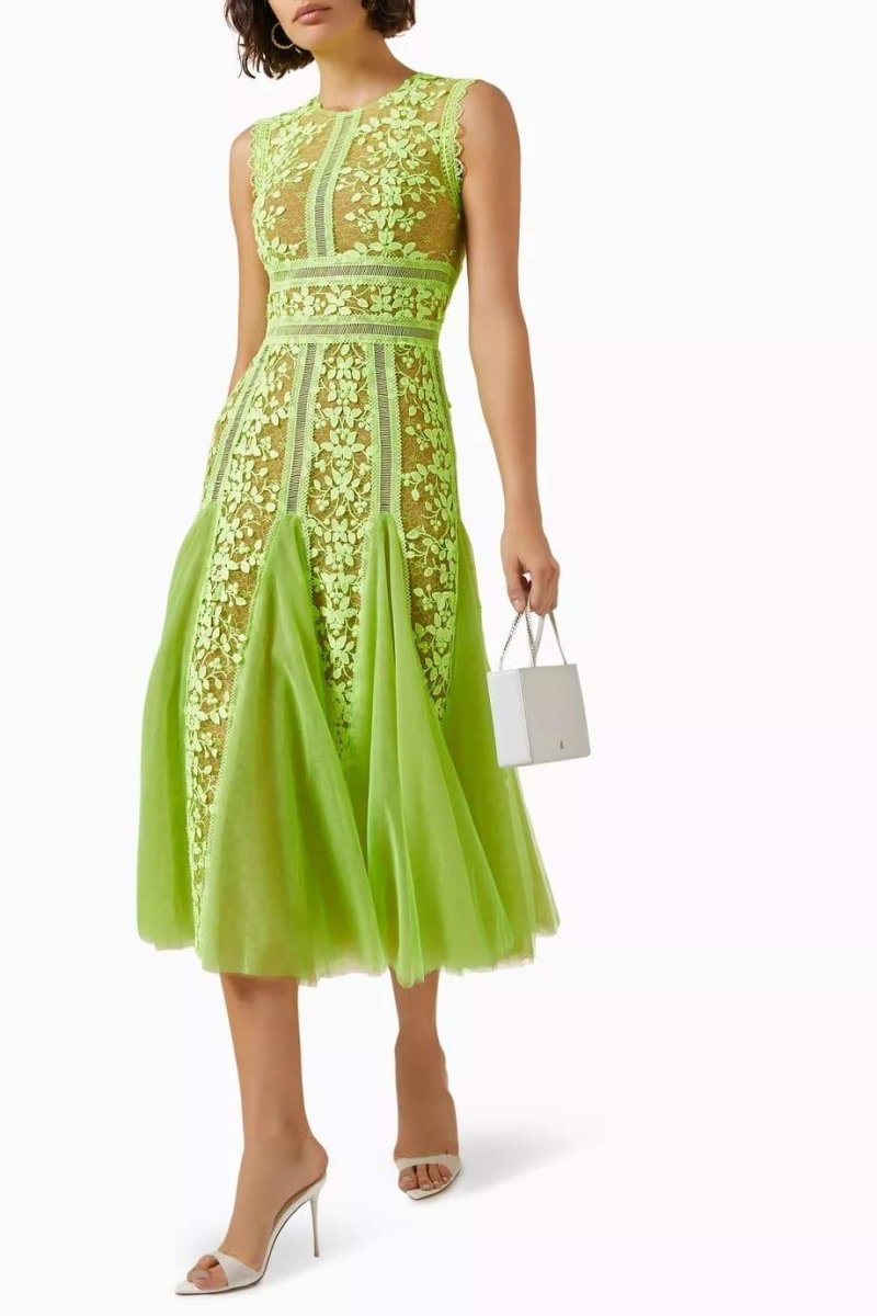 Woman in lime green floral lace midi dress with white handbag