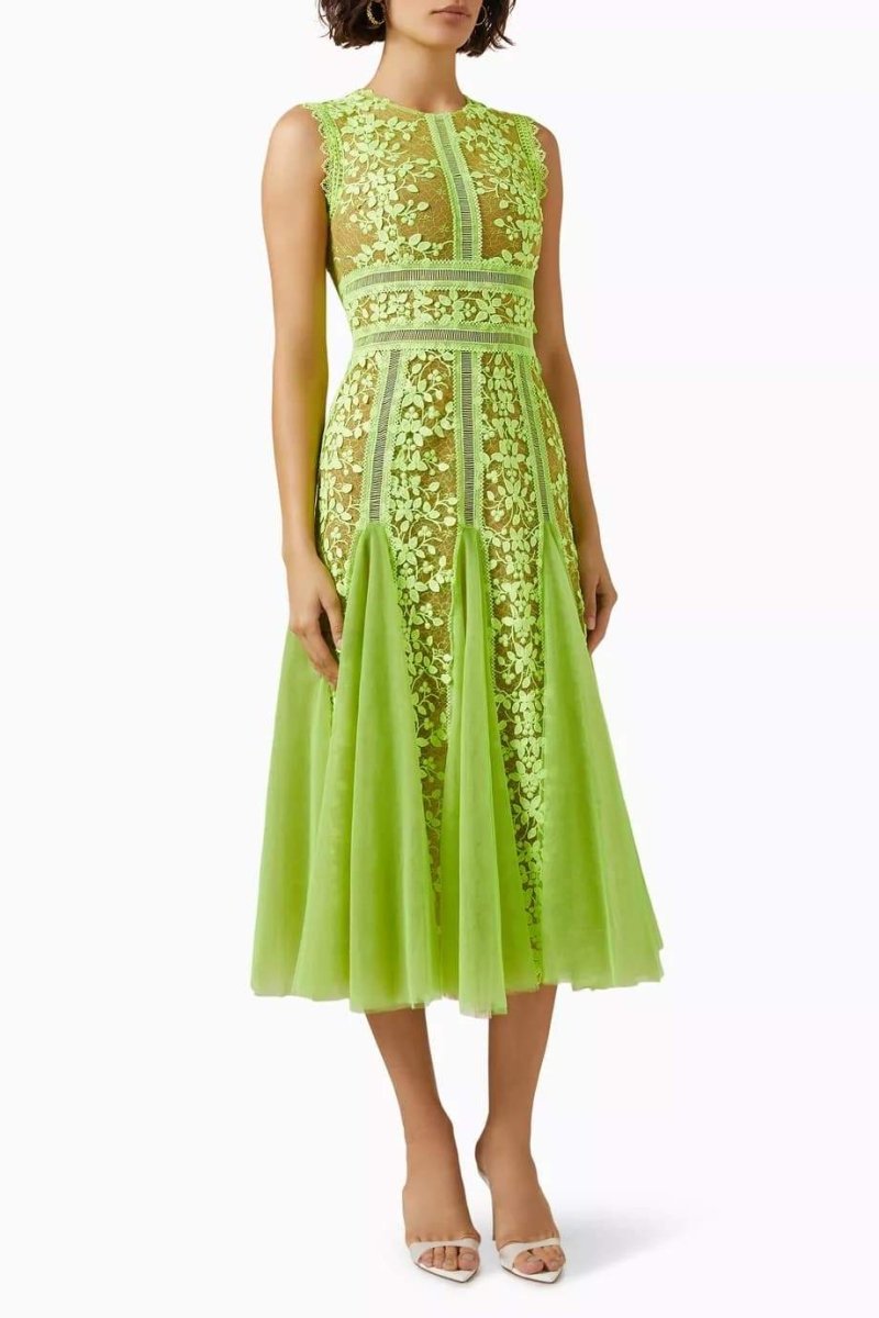Woman in lime green floral lace midi dress with white handbag