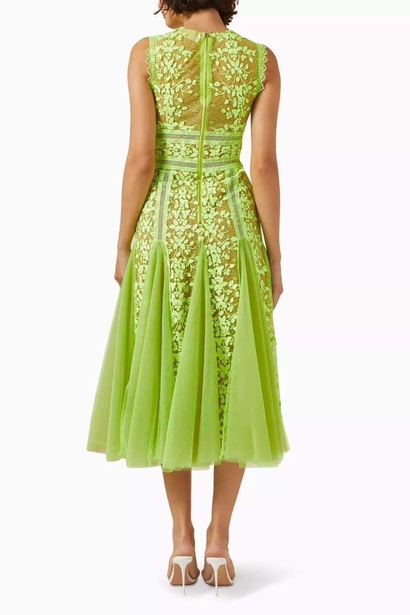 Woman in lime green floral lace midi dress with white handbag