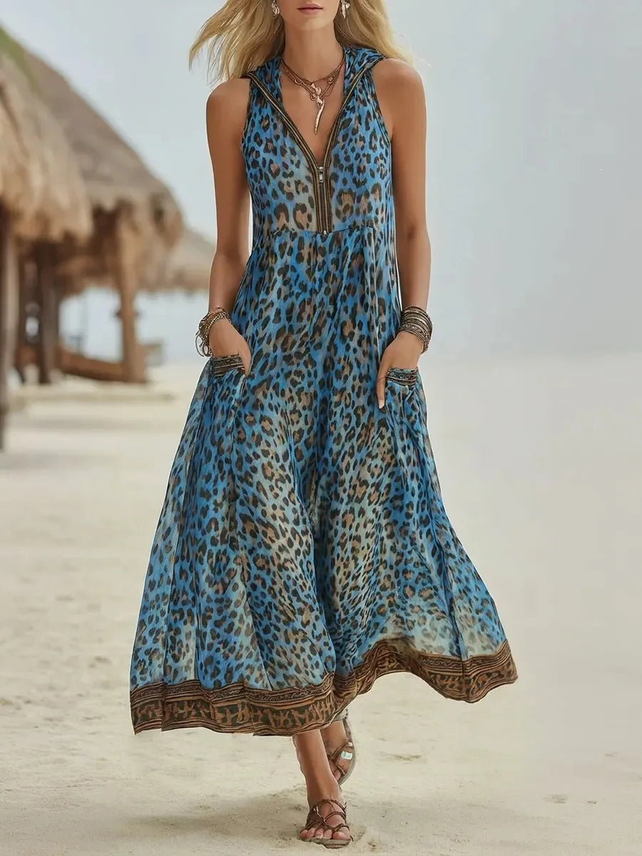 Blue - A woman walks on a sandy beach wearing a sleeveless, hooded green leopard print chiffon maxi dress with a zip-front neckline and side pockets.