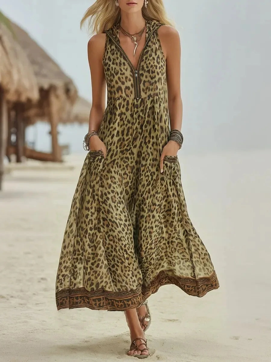 Khaki - A woman walks on a sandy beach wearing a sleeveless, hooded green leopard print chiffon maxi dress with a zip-front neckline and side pockets.