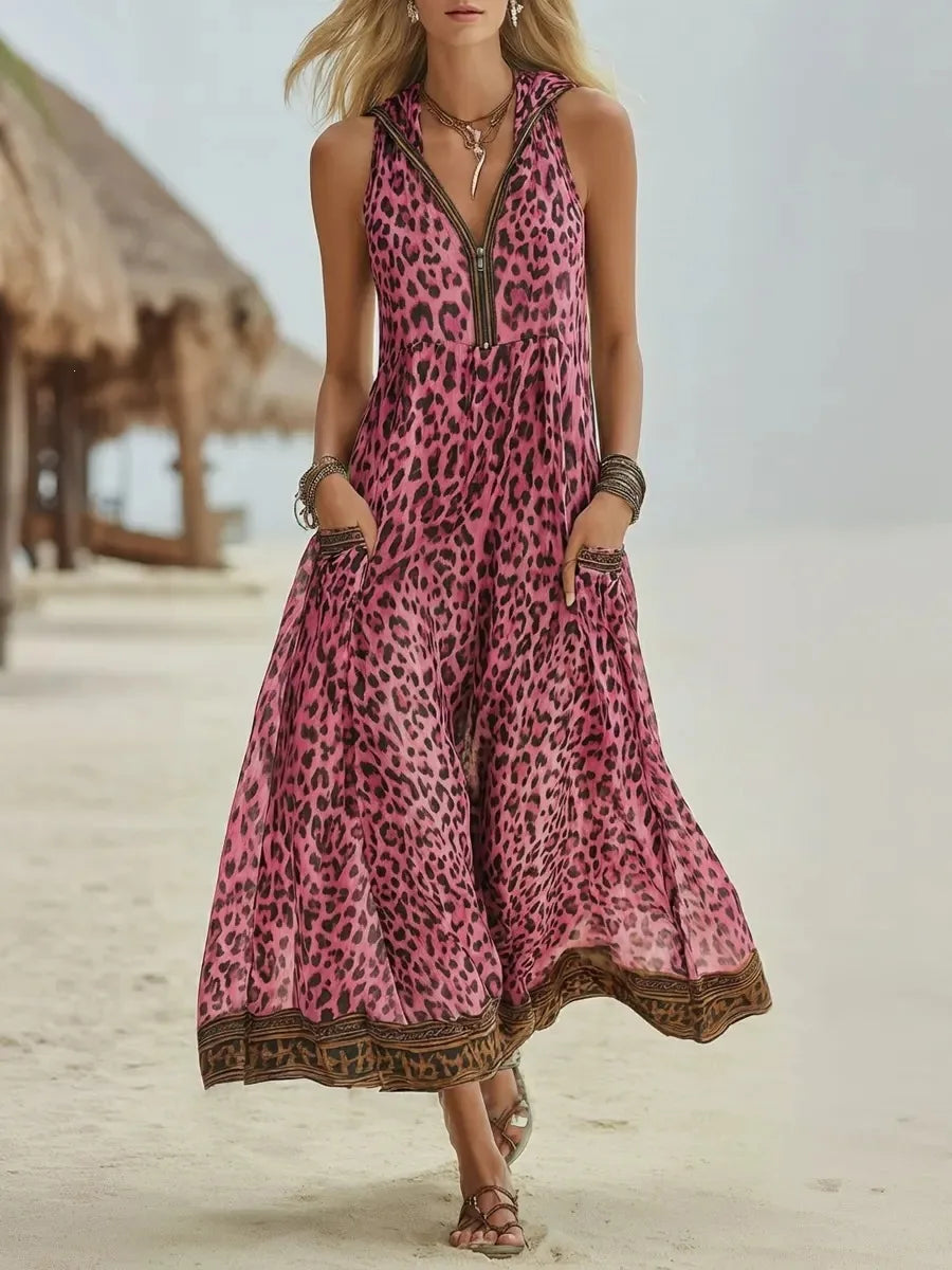 Pink - A woman walks on a sandy beach wearing a sleeveless, hooded green leopard print chiffon maxi dress with a zip-front neckline and side pockets.
