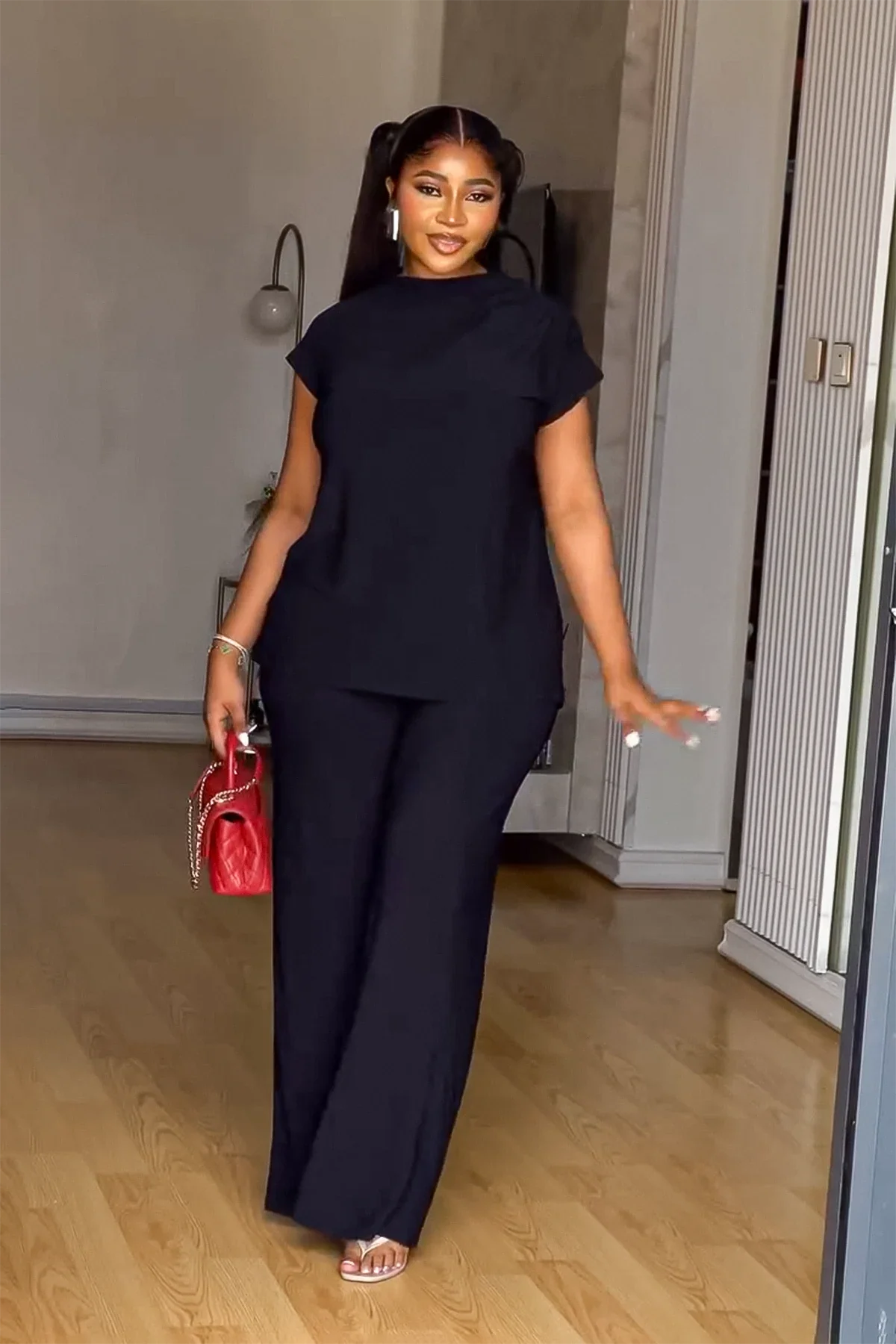Woman in black linen pant set with red handbag
