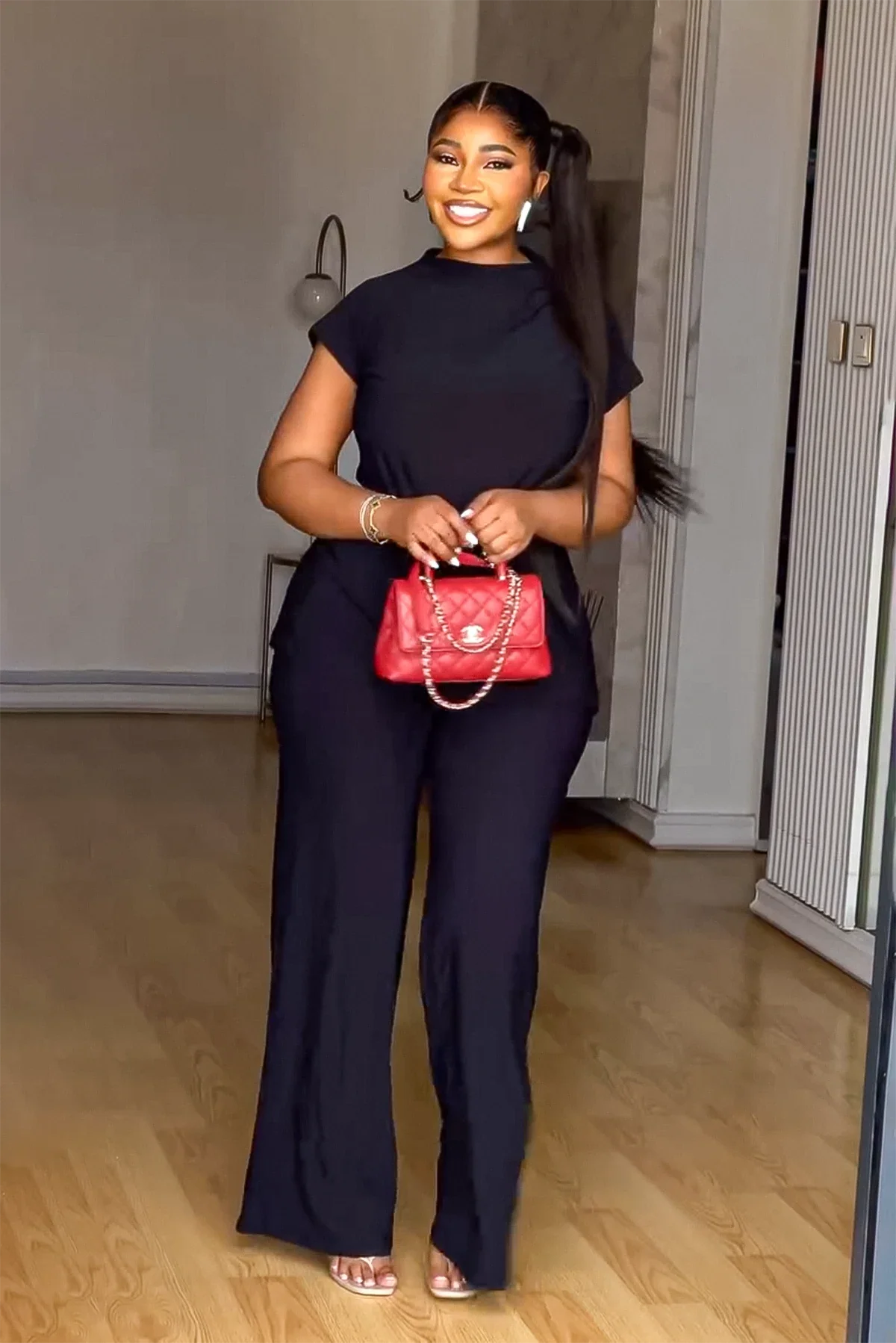 Woman in black linen pant set with red handbag