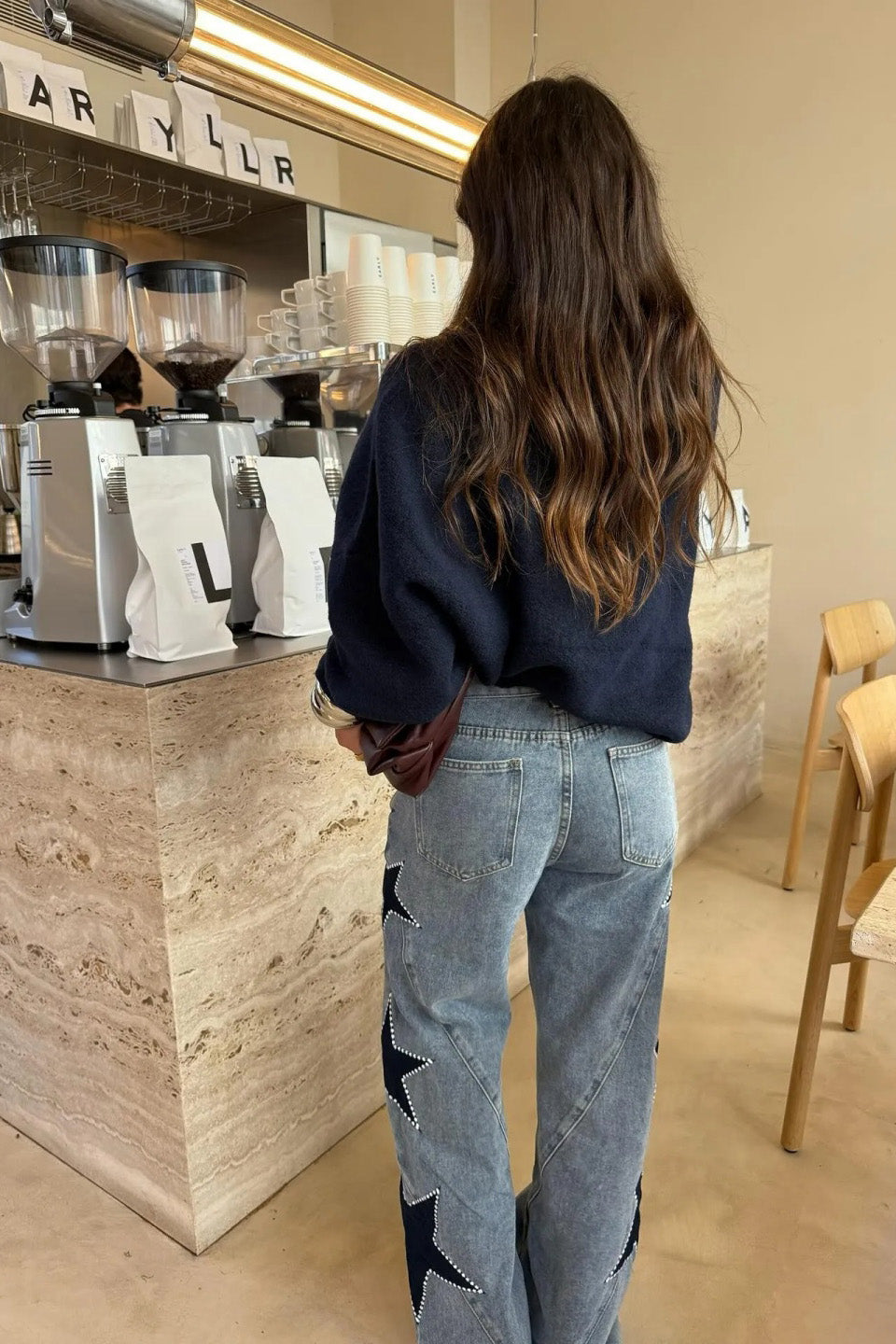 Woman wearing light wash wide leg jeans with star appliqués