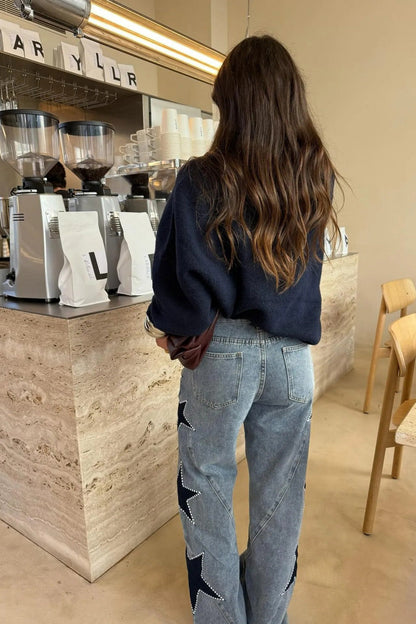 Woman wearing light wash wide leg jeans with star appliqués