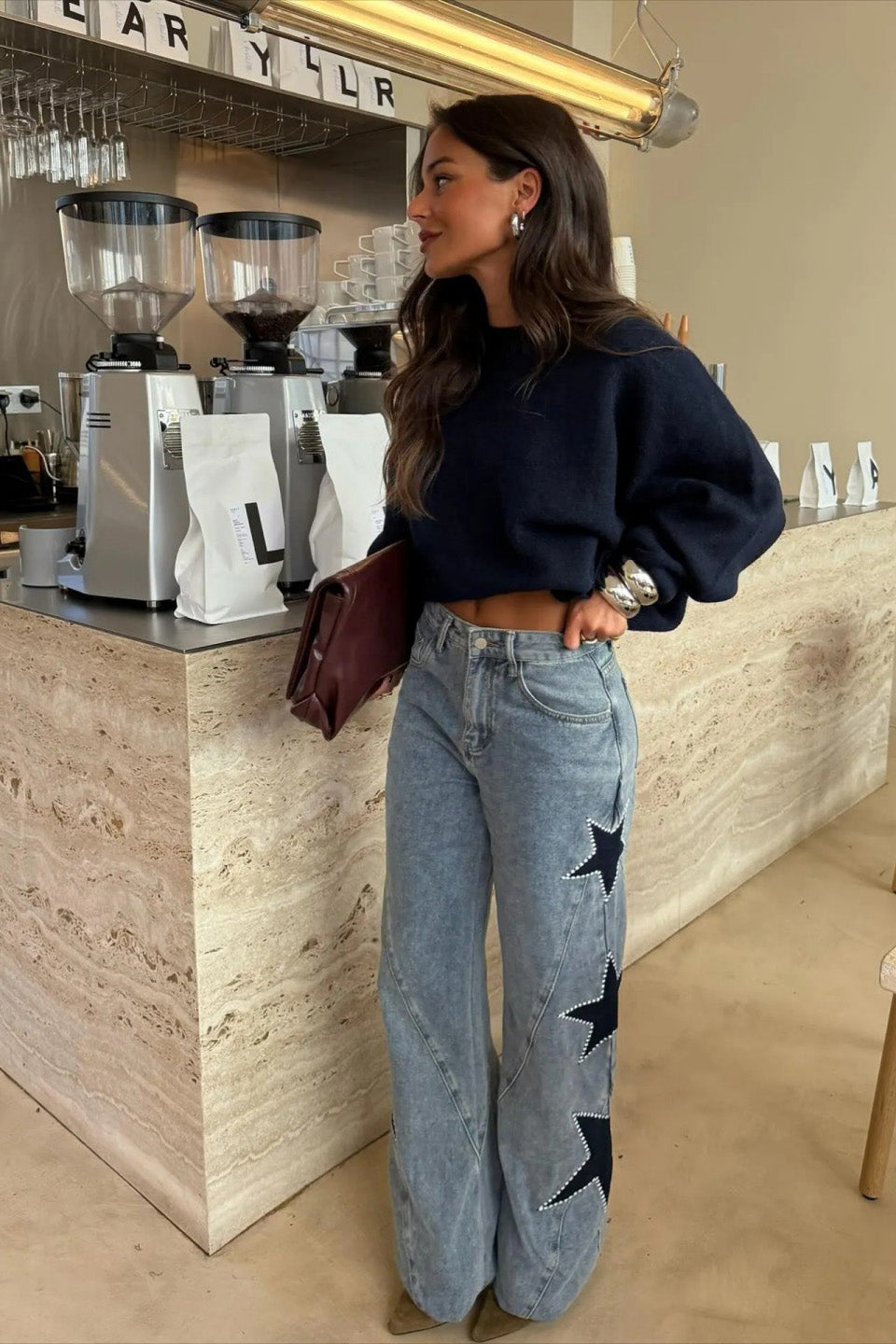 Woman wearing light wash wide leg jeans with star appliqués