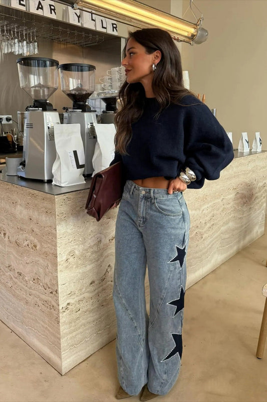 Woman wearing light wash wide leg jeans with star appliqués