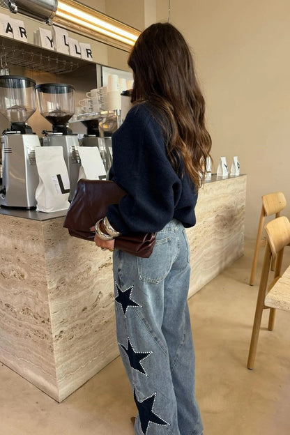 Woman wearing light wash wide leg jeans with star appliqués