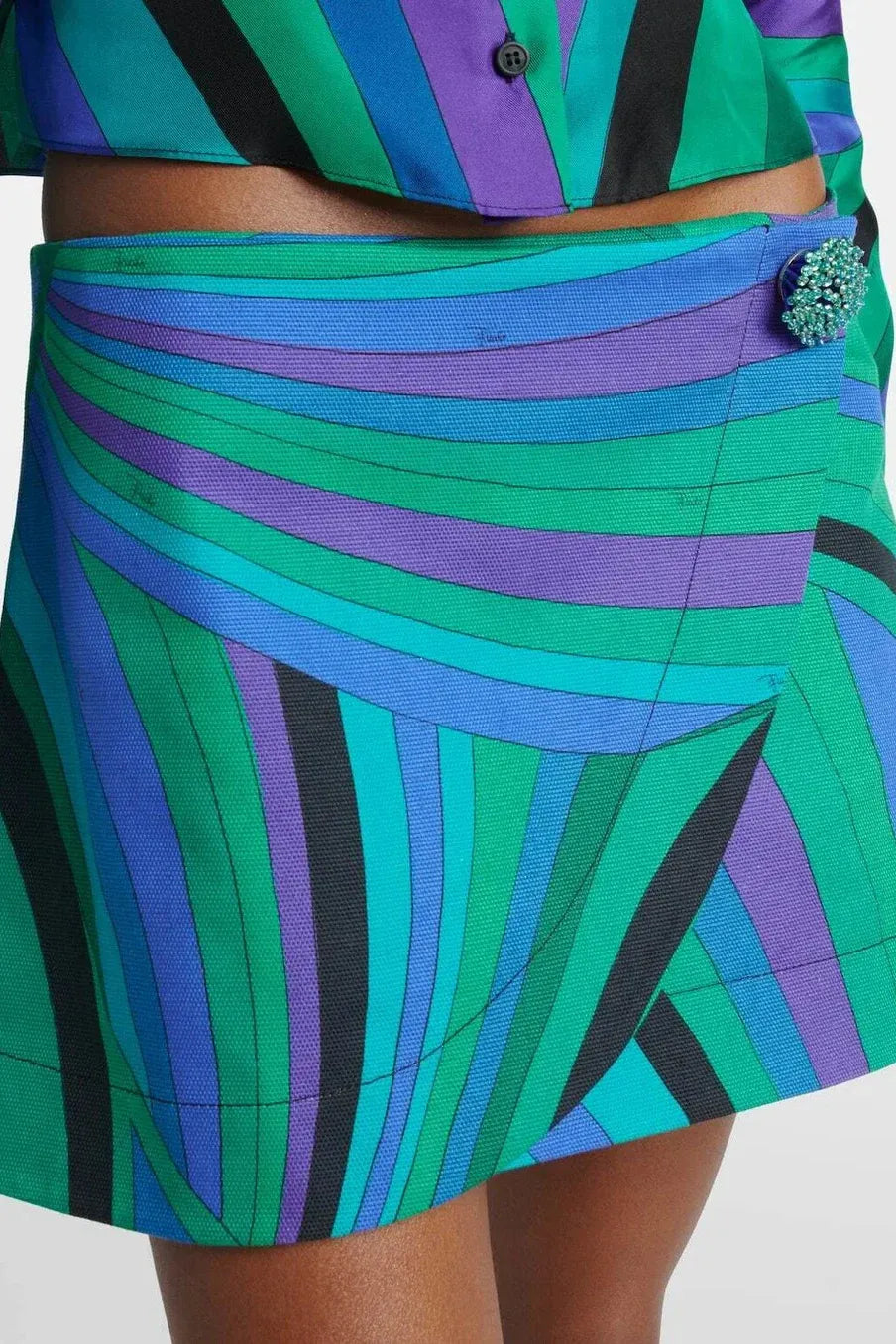 Woman in blue and green silk halter top and mini skirt with straw hat and beaded bag