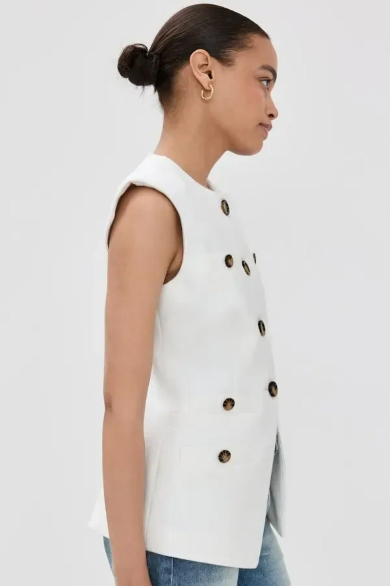 Woman wearing white boucle vest with tortoise buttons