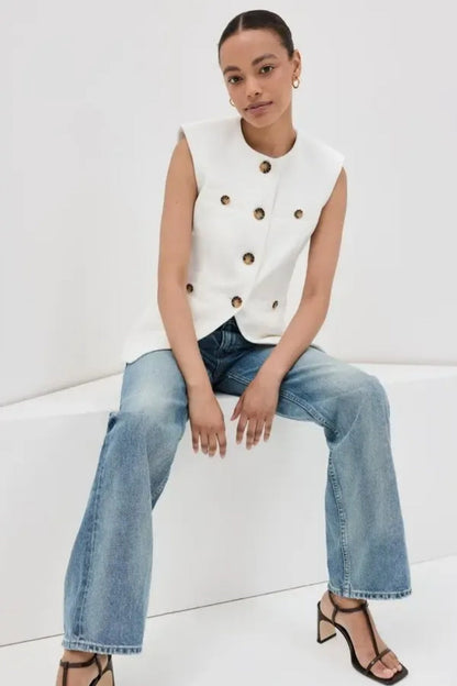 Woman wearing white boucle vest with tortoise buttons