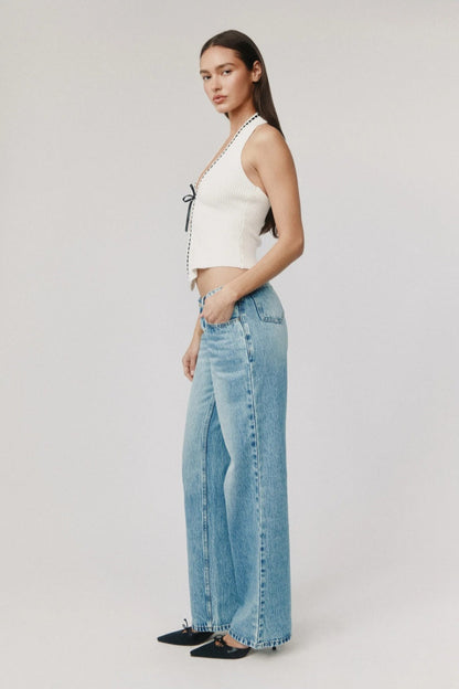 Woman in white ribbed knit halter top with black trim and tie front.