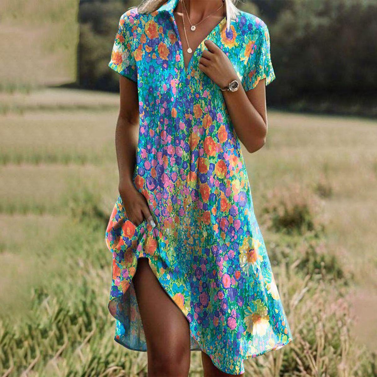 Multicolor - A woman wearing a vibrant multi-color impressionist floral print sundress with a V-neck collar, short sleeves, and side pockets, standing in a grassy field.