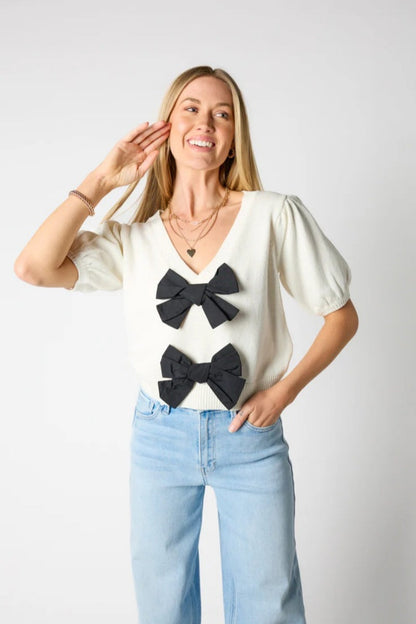 Woman wearing ivory ribbed knit cardigan with black bows