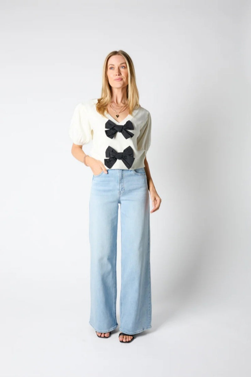 Woman wearing ivory ribbed knit cardigan with black bows