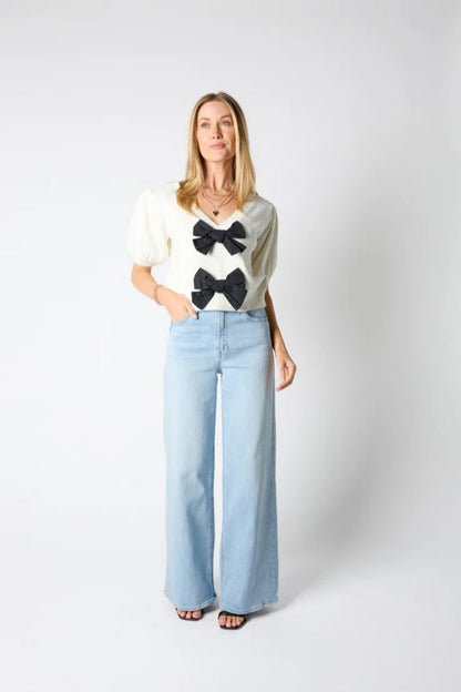 Woman wearing ivory ribbed knit cardigan with black bows