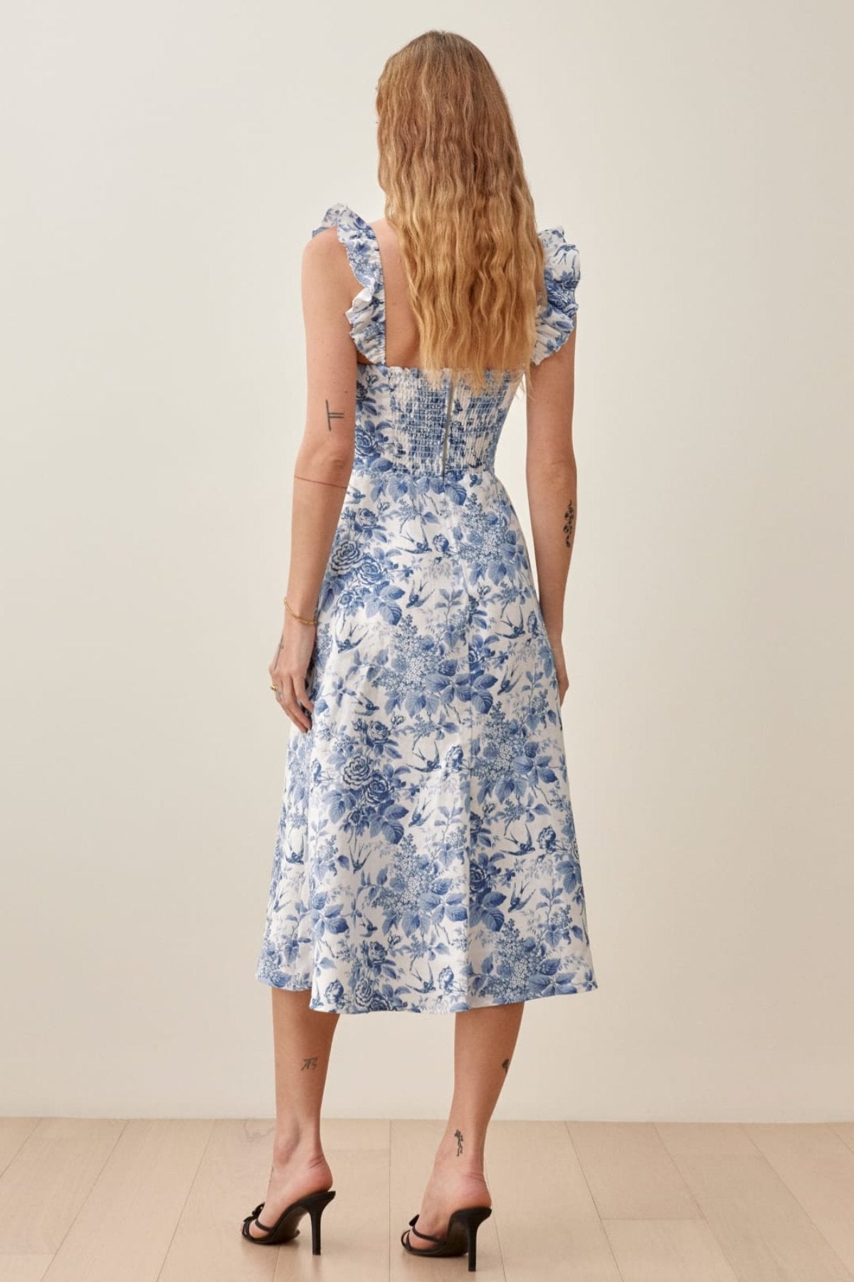 Woman wearing blue and white floral linen midi dress with ruffle straps and thigh slit