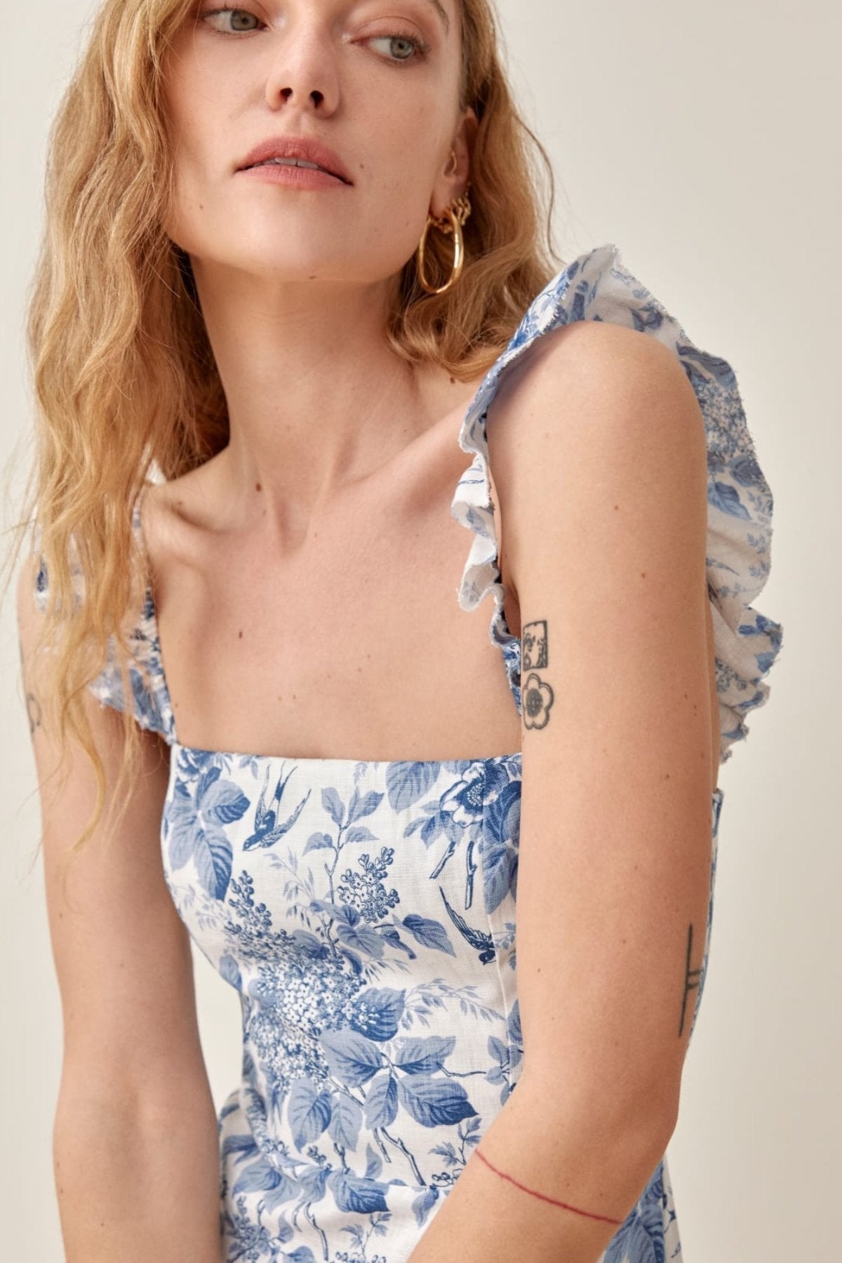 Woman wearing blue and white floral linen midi dress with ruffle straps and thigh slit