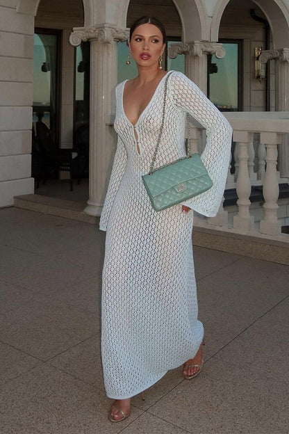 Woman wearing a long white crochet dress with a light blue purse.