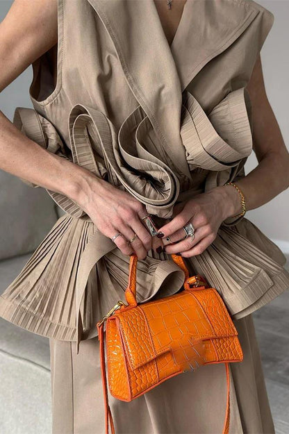 Woman wearing tan sleeveless trench vest with orange purse